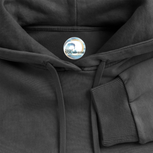 Close-up van Sacred YOUniverse logolabel binnenin de capuchon van de zuurgewassen zwarte unisex hoodie van 100% katoen, kwaliteitsdetail
