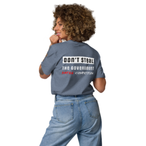 Vrouw gezien van achteren in denim blauw T-shirt met opdruk "Don't Steal. The Government Hates Competition" in zwart, wit en rood.