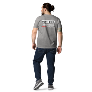 Man gezien van achteren draagt melange grijs T-shirt met opdruk "Don't Steal. The Government Hates Competition." in zwart, wit en rood, gecombineerd met donkerblauwe jeans en sneakers.